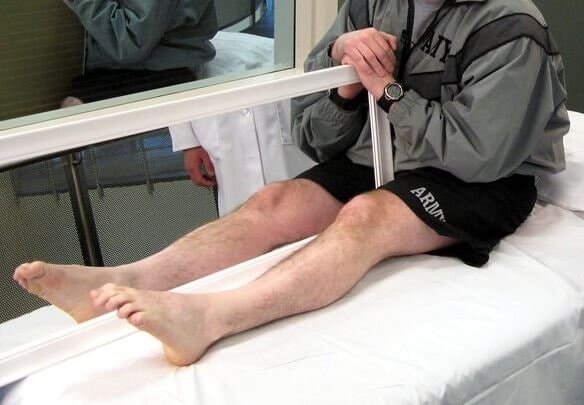 A patient holding a mirror to reflect his intact limb as part of mirror therapy.