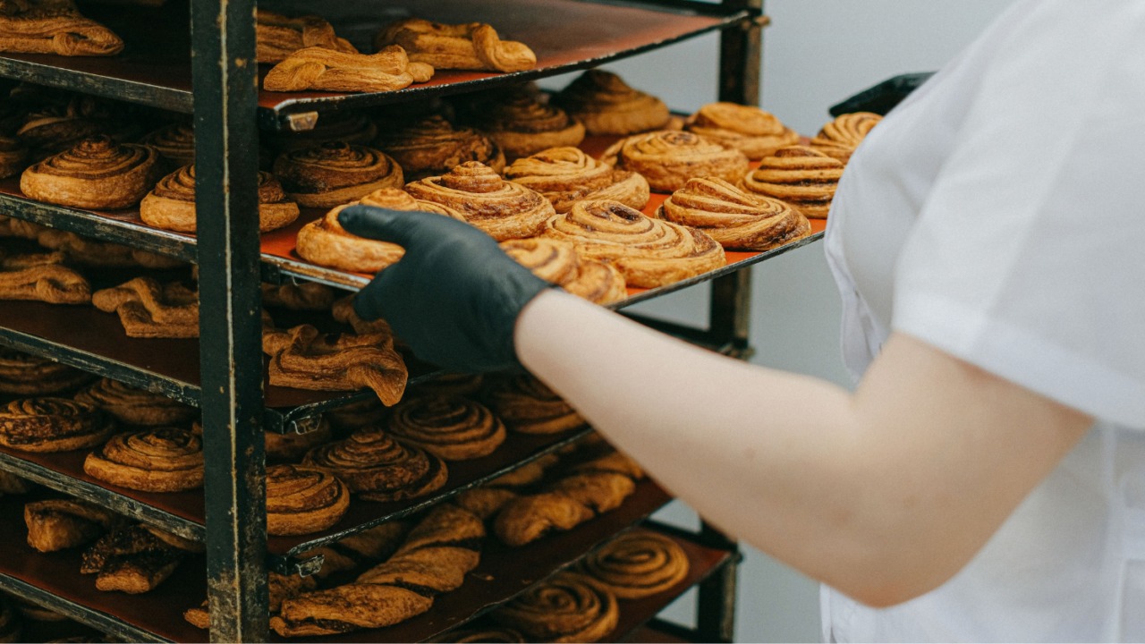 Trays of cinnamon rolls fresh from the oven on a bakery rack